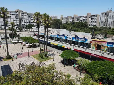 a train in a city with palm trees and buildings at Elegant and spacious penthouse in Lima