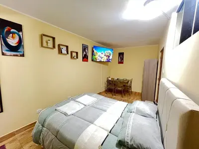 a bedroom with a bed and a tv on the wall at Habitaciones privadas para alojamiento en Ica, Perú in Ica
