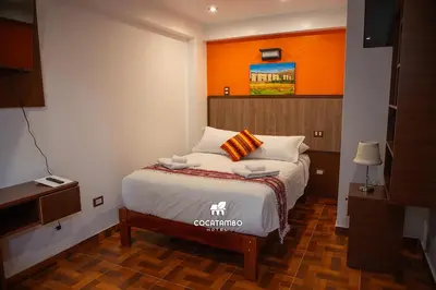 a bedroom with a bed with an orange wall at Cocatambo in Ollantaytambo