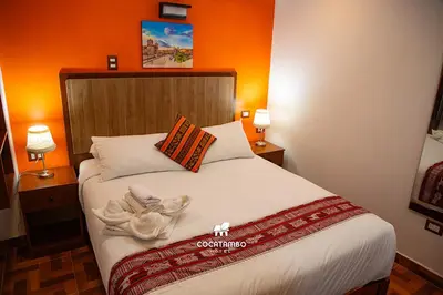 a bedroom with a bed with an orange wall at Cocatambo in Ollantaytambo