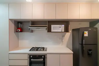 a small kitchen with a black refrigerator and white cabinets at Edificio Parque Castilla in Lima