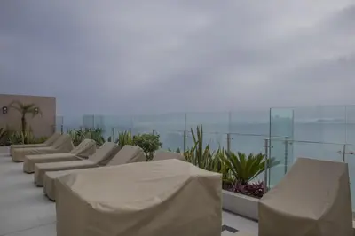 a row of white chairs on a balcony with the ocean at Sight Oceanview in Barranco Malecon by Wynwood House in Lima
