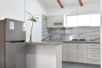 a kitchen with a stainless steel refrigerator and white cabinets at Apart Hotel El Puma in Cusco