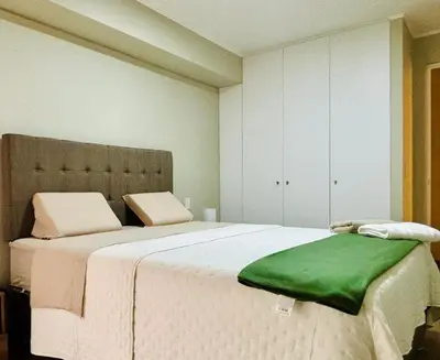 a bedroom with a large bed with a green blanket on it at Modern and centrally located with a rooftop in Lima
