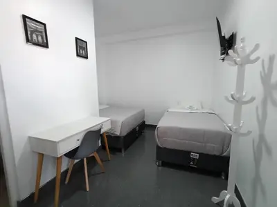 a room with two beds and a desk and a sink at Hospedaje Altamar in Paracas