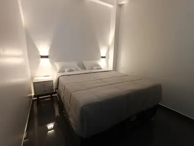 a small bedroom with a bed and two lamps at Hospedaje Altamar in Paracas