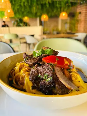 a bowl of food with meat and noodles on a table at Senoma Hotel - Adults only in Ica