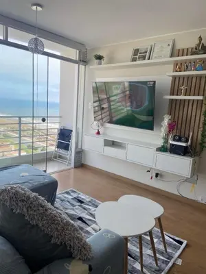a living room with a tv and a couch and a table at Departamento Costanera frente al mar in Lima