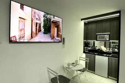 a kitchen with a table and a tv on a wall at Wake Up Near The Sea in Lima