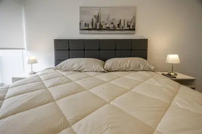 a large white bed in a bedroom with two lamps at BSR Flat los Andes near Airport in Lima