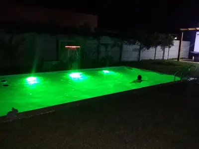 a pool with green lights in a yard at night at Condominio ecológico las gardenias de Asia