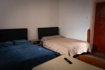 a room with two beds and a table in it at Mini apartment in downtown Cusco in Cusco