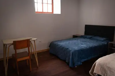 a bedroom with a bed and a desk and a window at Mini apartment in downtown Cusco in Cusco
