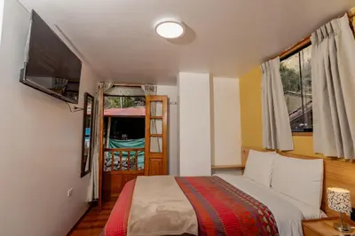 a bedroom with a bed and a tv and a window at Kamma Guest House in Ollantaytambo