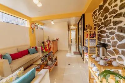 a living room with a couch and a stone wall at Kamma Guest House in Ollantaytambo