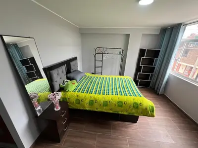 a bedroom with a bed with a yellow comforter and a mirror at Alojamiento ideal Equipado in Huancayo