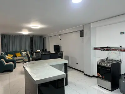 a kitchen with a stove and a living room at Alojamiento ideal Equipado in Huancayo