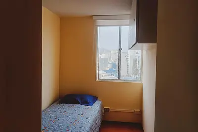 a small bedroom with a bed and a window at Apartamento cómodo con piscina en el Centro Histórico, Lima in Lima