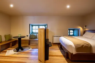 a bedroom with a bed and a table and two windows at Hotel 1821 in Cusco