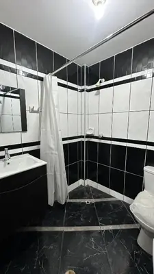 a black and white bathroom with a toilet and a sink at Habitación privada a 20 min del Aeropuerto de LIMA in Lima