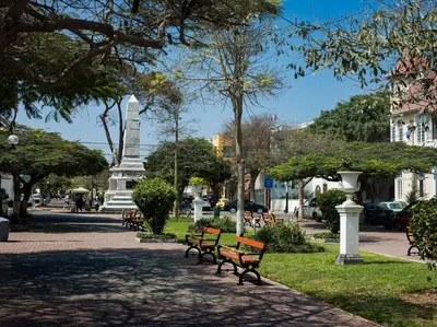 a park with benches and a monument in the background at Departamento en Barranco in Lima