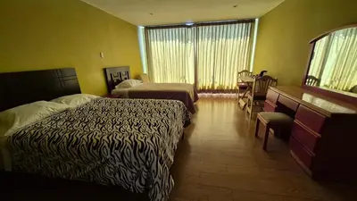 a hotel room with two beds and a desk at Dormitorio con baño privado a 25 minutos del Apto in Lima