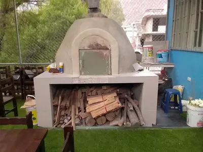 an outdoor pizza oven with fire wood in it at Hospedaje TUTUMEME in Churín