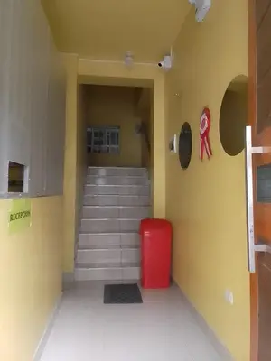 a hallway with stairs and a red suitcase in a building at Hospedaje TUTUMEME in Churín