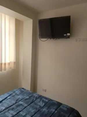 a bedroom with a bed and a flat screen tv on the wall at Hospedaje TUTUMEME in Churín
