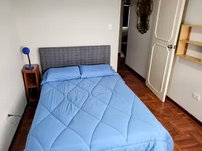a bed in a room with a blue comforter at Entire Apartment in Miraflores in Lima