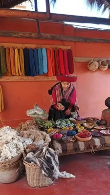 a woman sitting on a table in a market at Hotel Inka House Chinchero in Chinchero