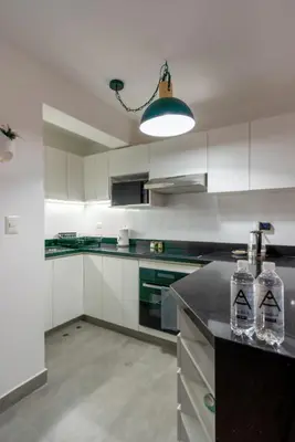 a kitchen with white cabinets and a black counter top at Nuvee 2BR by Geko in Lima