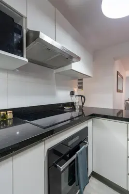 a kitchen with white cabinets and a stove top oven at Nuvee 2BR by Geko in Lima