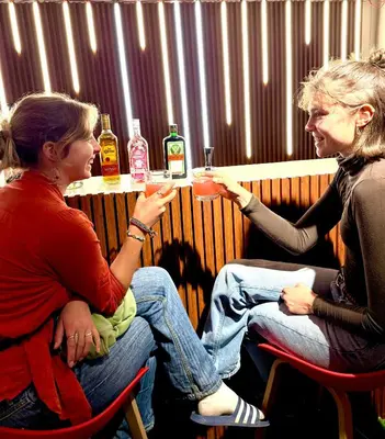 two women sitting at a bar with drinks at Lima Hostel - Barranco in Lima