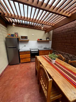 a kitchen with a wooden table and a refrigerator at Charming Urubamba Cusco house - Kapuliyuq in Urubamba