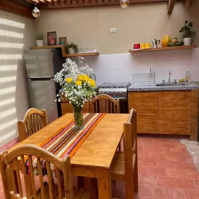 a kitchen with a wooden table with a vase of flowers on it at Charming Urubamba Cusco house - Kapuliyuq in Urubamba