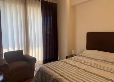a bedroom with a bed and a chair and a window at Qori Apartment in Cusco