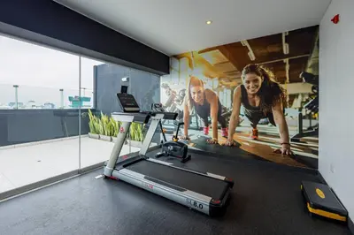 a woman on a treadmill in a gym with a poster at BSR Romantic Escape Flat w/ Rooftop Pool in Lima