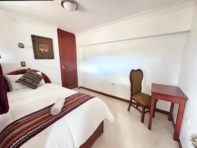 a bedroom with a bed and a desk and a chair at Libertrek in Cusco