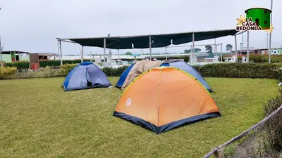 two tents sitting on the grass in a field at La Casa Redonda - Supe in Barranca