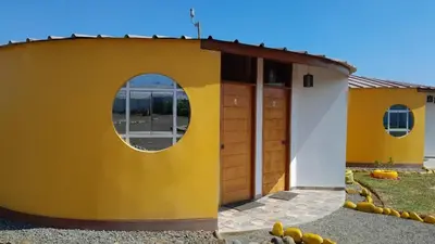 a yellow and white building with a round window at La Casa Redonda - Supe in Barranca