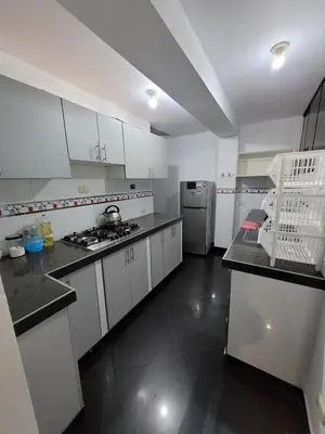 a kitchen with white cabinets and a refrigerator at Departamento cerca del aeropuerto in Lima