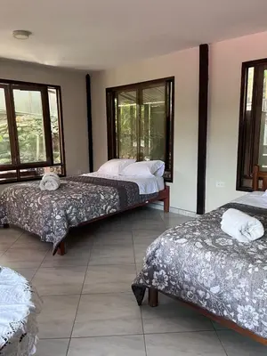 two beds in a room with windows at Montañita Lodge in La Merced