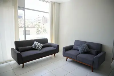 a couch and a chair in a room with a window at Jatun Coya in Huancayo