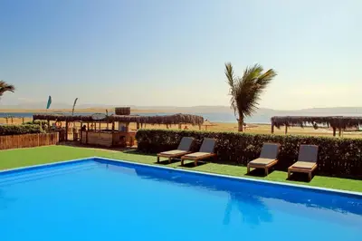 a swimming pool with two chairs and the beach at Bamboo Paracas Hotel in Paracas