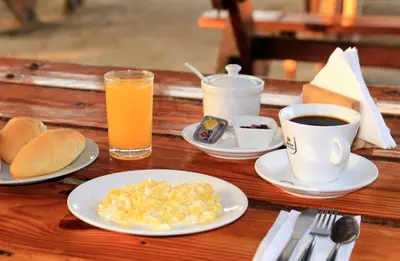a table with plates of eggs and cups of coffee at Bamboo Paracas Hotel in Paracas