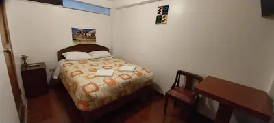 a small bedroom with a bed and a desk at Catari's House in Machu Picchu