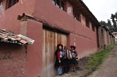 three women standing in front of a red building at Casa de gumercindo in Coper