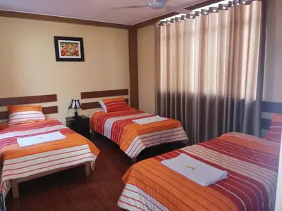 a hotel room with three beds and curtains at Nasca Travel One Hostel in Nazca