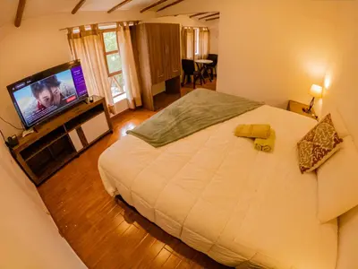 a bedroom with a large bed and a flat screen tv at Kay Pacha Wellness Place Eco in Ayacucho